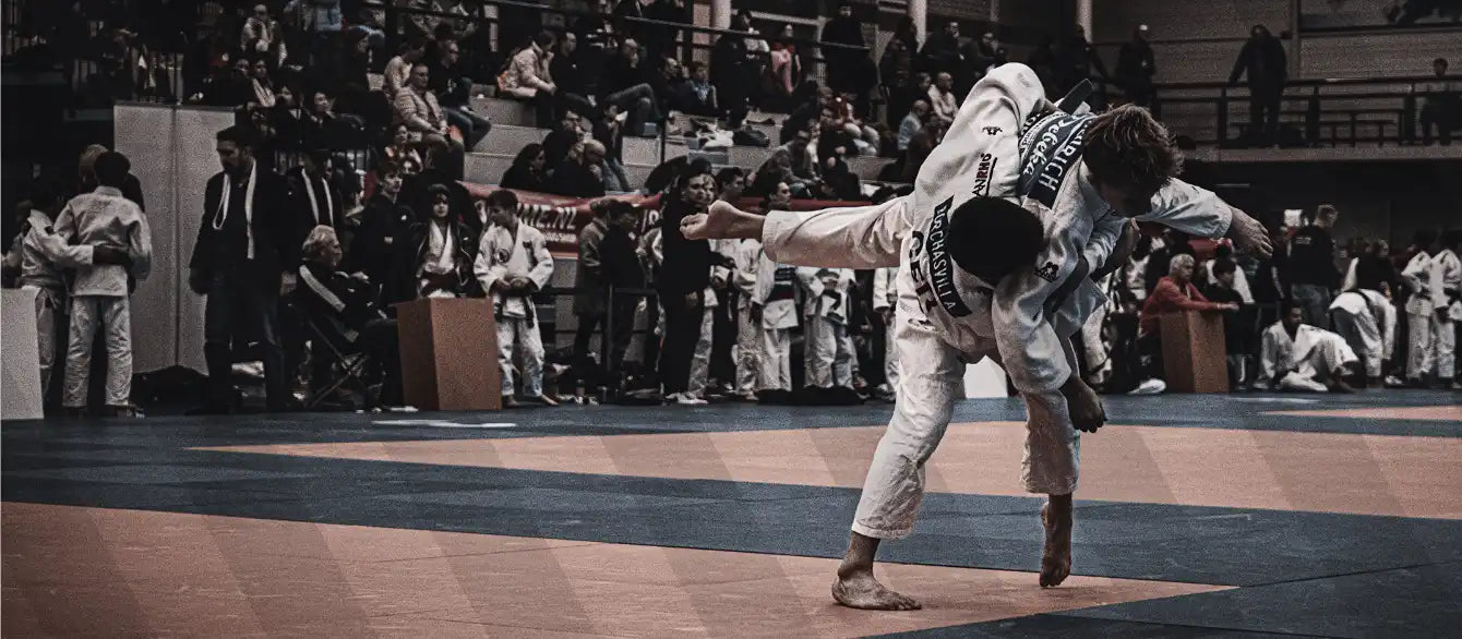 Judoka's in wit pak die worp uitvoeren voor publiek tijdens een wedstrijd