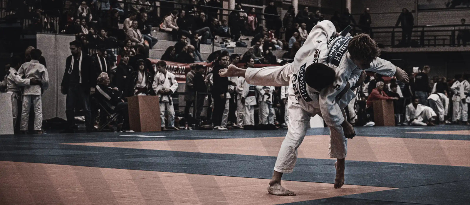 Judoka's in wit pak die worp uitvoeren voor publiek tijdens een wedstrijd